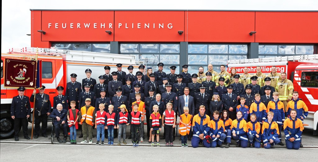 Gruppenfoto der Feuerwehr Pliening mit aktiver Mannschaft, Jugend- und Kinderfeuerwehr vor dem Feuerwehrhaus